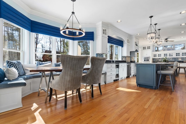 dining room featuring beverage cooler, light wood finished floors, recessed lighting, ornamental molding, and breakfast area