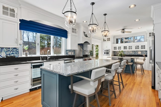 kitchen featuring wine cooler, white cabinetry, a center island, and tasteful backsplash