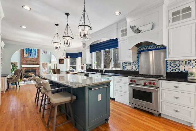 kitchen featuring backsplash, a kitchen island, open floor plan, stainless steel appliances, and a brick fireplace