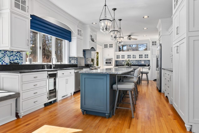 kitchen with a breakfast bar, stainless steel appliances, white cabinetry, backsplash, and a center island