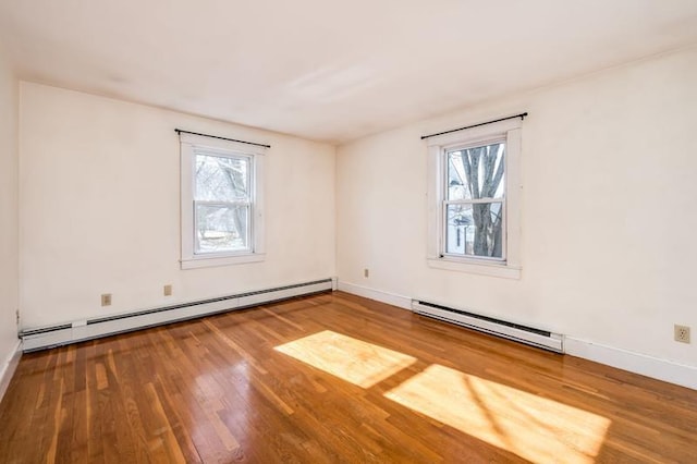 empty room featuring baseboard heating, wood finished floors, baseboards, and a baseboard radiator