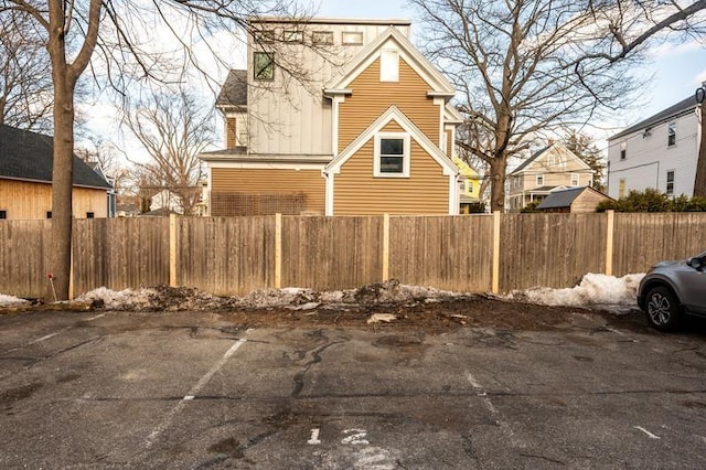 view of side of property featuring a fenced front yard and uncovered parking