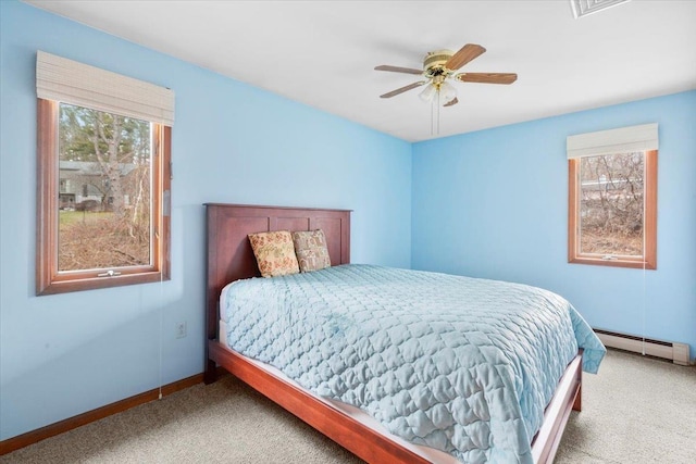 carpeted bedroom with a baseboard heating unit, baseboards, and a ceiling fan