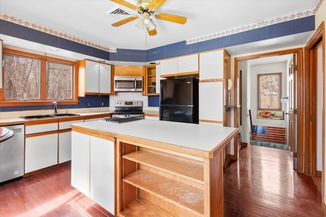 kitchen with a sink, white cabinets, appliances with stainless steel finishes, and open shelves