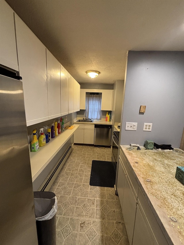 kitchen with a sink, a baseboard heating unit, white cabinetry, appliances with stainless steel finishes, and light countertops