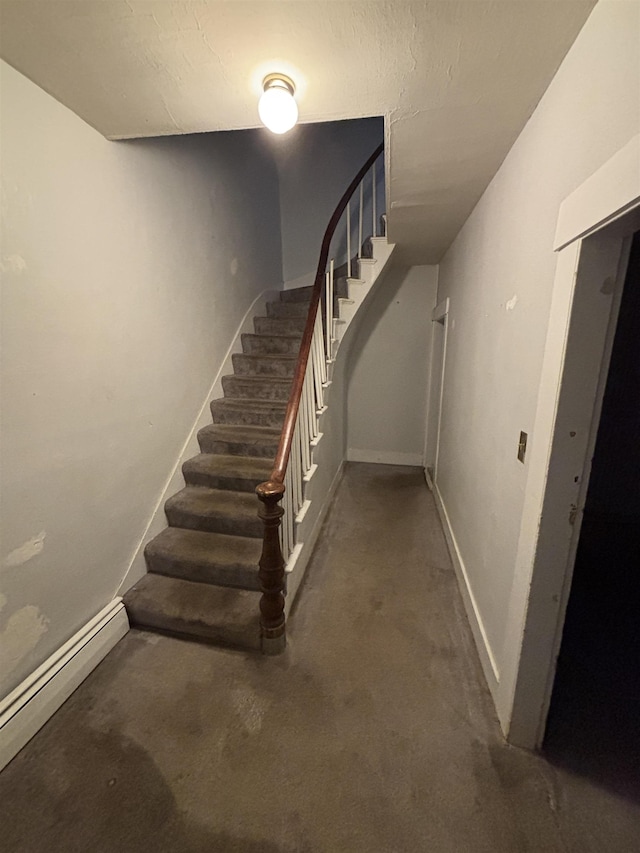 stairs featuring baseboards, concrete floors, and a baseboard radiator