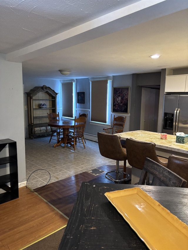 dining space with a baseboard heating unit and wood finished floors