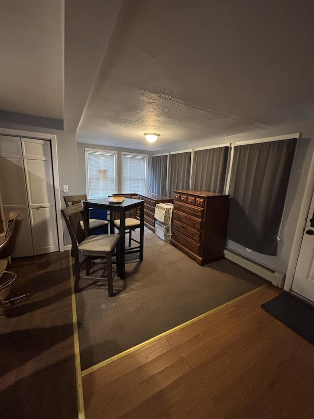 dining room with dark wood finished floors, a textured ceiling, and a baseboard radiator