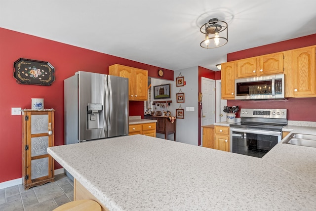 kitchen with a peninsula, stainless steel appliances, light countertops, and baseboards