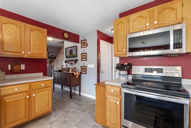 kitchen featuring light countertops, stone finish flooring, baseboards, and stainless steel appliances