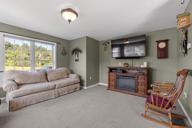 carpeted living area featuring visible vents, baseboards, and a glass covered fireplace