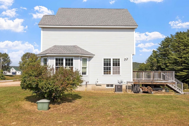 rear view of property with a deck, central AC unit, a yard, and roof with shingles