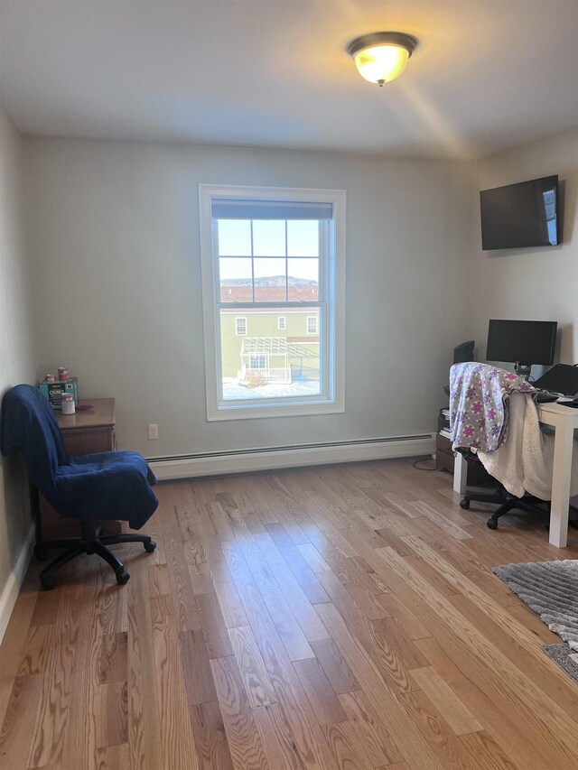 office with a baseboard heating unit, baseboards, and light wood-style floors