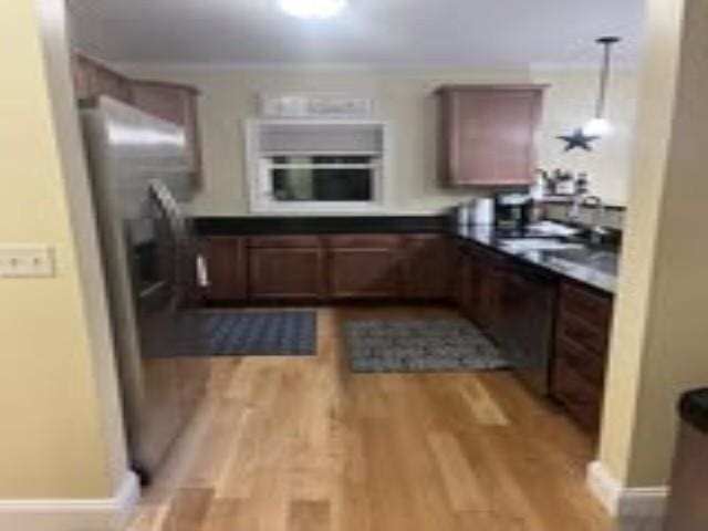 kitchen with light wood finished floors, dark countertops, oven, baseboards, and decorative light fixtures