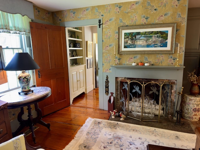 sitting room featuring hardwood / wood-style flooring, a fireplace, and wallpapered walls