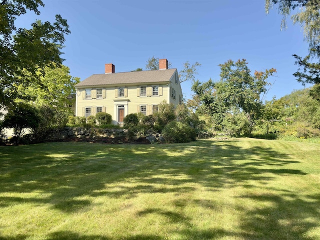 colonial house with a chimney and a front yard