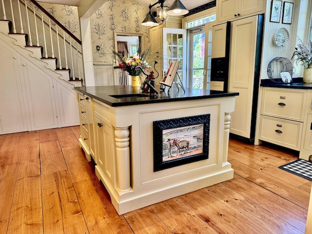 kitchen with light wood-style floors, dark countertops, a center island, and wallpapered walls