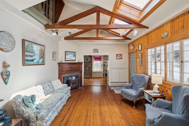 living room featuring hardwood / wood-style floors, a healthy amount of sunlight, a skylight, and a wood stove