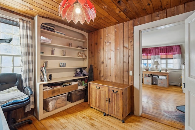 home office featuring wood walls, wooden ceiling, light wood-style floors, and a baseboard radiator