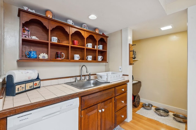 kitchen with baseboards, open shelves, white dishwasher, a sink, and light wood-type flooring