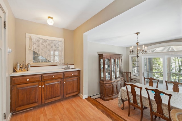 dining area with a baseboard heating unit, baseboards, light wood-style floors, and a chandelier