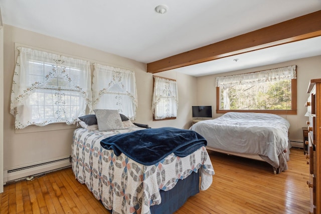 bedroom with a baseboard heating unit, beam ceiling, and light wood-style flooring