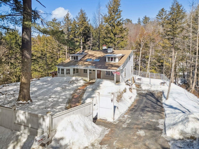 view of front of home featuring driveway, a wooded view, and a fenced front yard