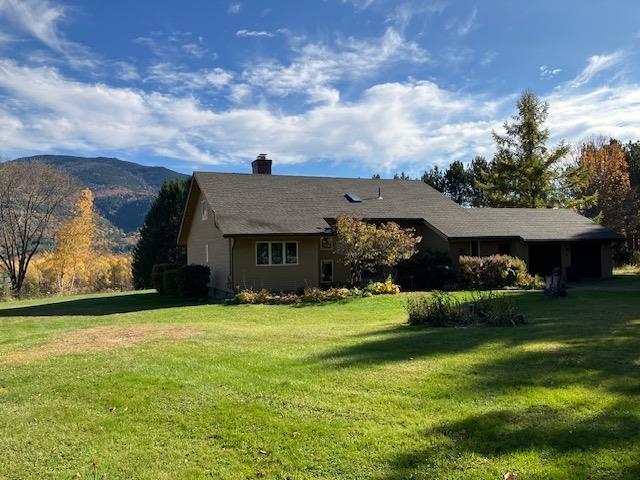 view of front facade featuring a mountain view, a chimney, and a front lawn