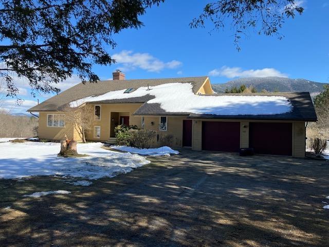 ranch-style home featuring a garage, a chimney, and driveway