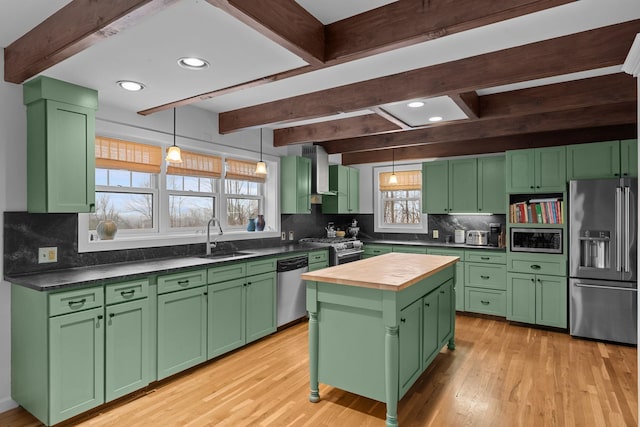 kitchen featuring green cabinets, butcher block counters, premium appliances, wall chimney exhaust hood, and a sink