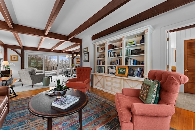 living room featuring beam ceiling, a notable chandelier, and wood finished floors