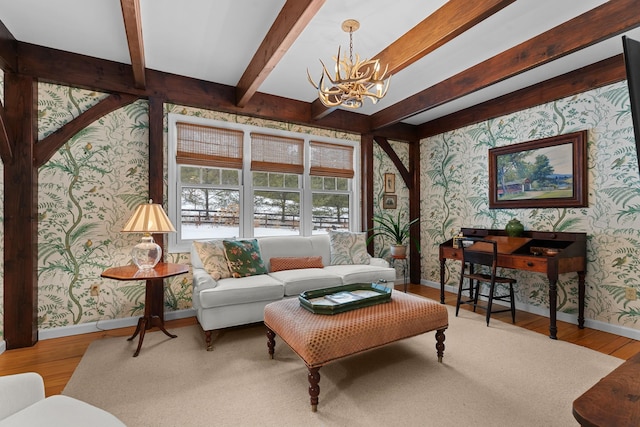 living room featuring beam ceiling, a notable chandelier, wood finished floors, and wallpapered walls