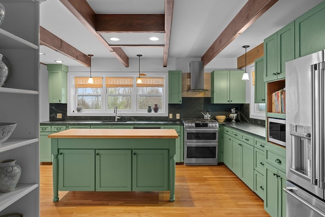 kitchen with green cabinetry, stainless steel appliances, island range hood, and a sink