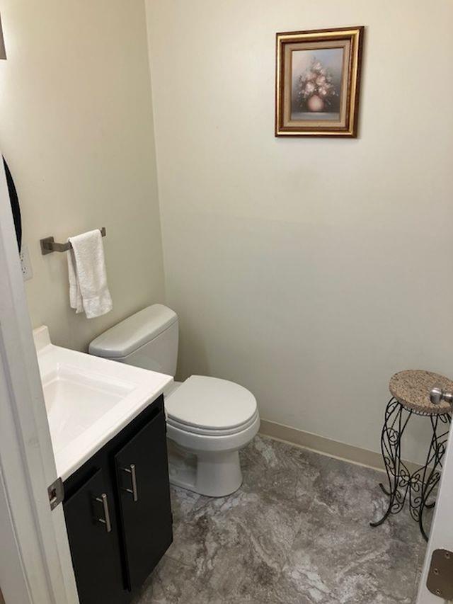 bathroom featuring vanity, toilet, and baseboards