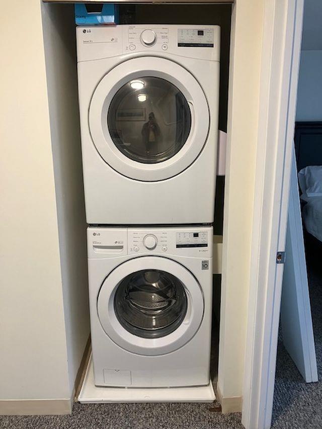 clothes washing area with laundry area, stacked washing maching and dryer, and baseboards