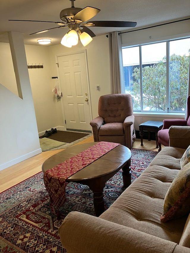 living room featuring baseboards, ceiling fan, and wood finished floors