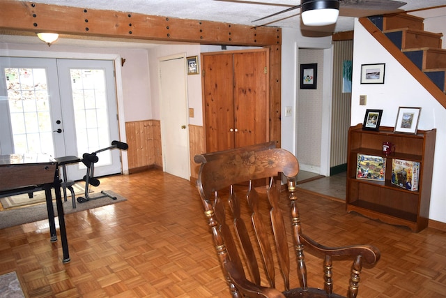 dining space featuring french doors, a wainscoted wall, a ceiling fan, and stairway