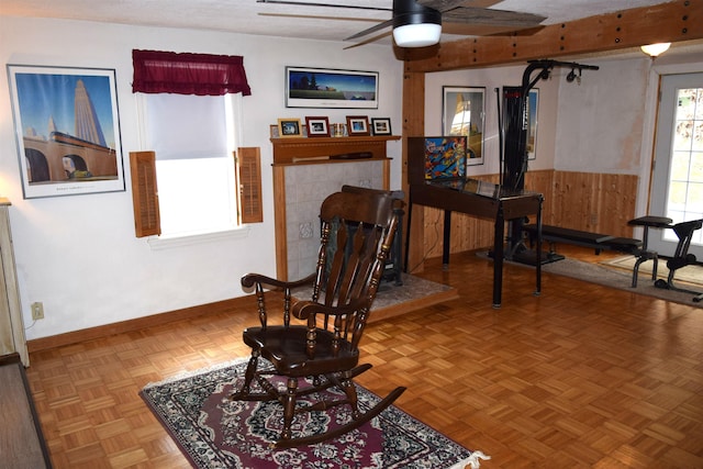 living area featuring a ceiling fan, baseboards, and a tile fireplace