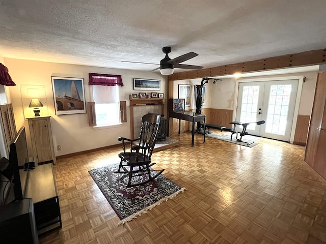 living area with plenty of natural light, french doors, a textured ceiling, and ceiling fan