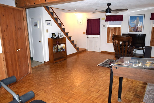 playroom featuring baseboards, a textured ceiling, and ceiling fan