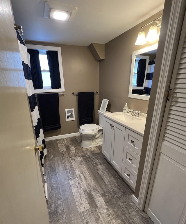 full bathroom with toilet, heating unit, wood finished floors, baseboards, and vanity