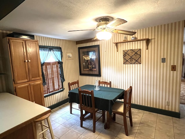 dining area featuring a textured ceiling, wallpapered walls, and baseboards