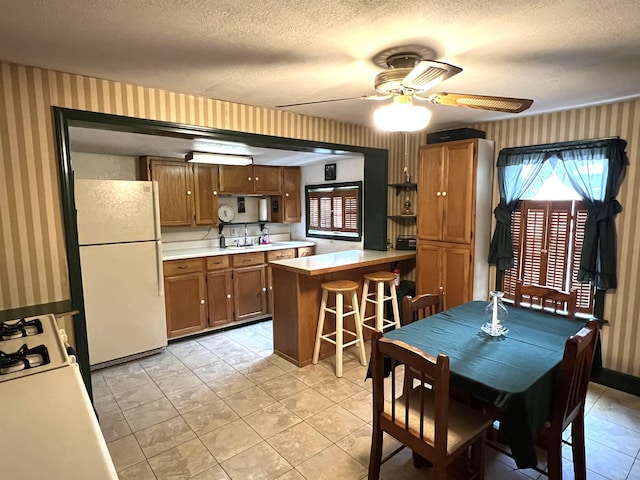 dining room featuring light tile patterned floors, a textured ceiling, wallpapered walls, and ceiling fan