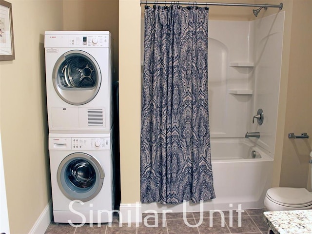 washroom featuring tile patterned floors, laundry area, baseboards, and stacked washer and dryer