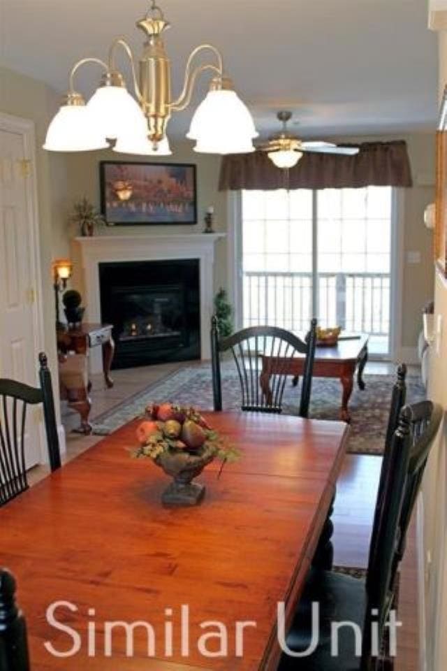 dining room with a glass covered fireplace and ceiling fan with notable chandelier