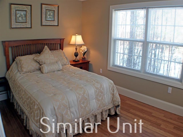 bedroom featuring multiple windows, baseboards, and wood finished floors