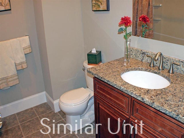 bathroom with tile patterned flooring, toilet, vanity, and baseboards