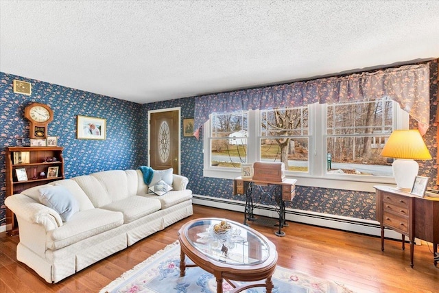 living room with a textured ceiling, wallpapered walls, a baseboard heating unit, and wood finished floors