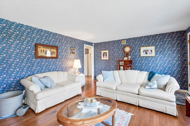 living room with wallpapered walls, wood finished floors, and a textured ceiling