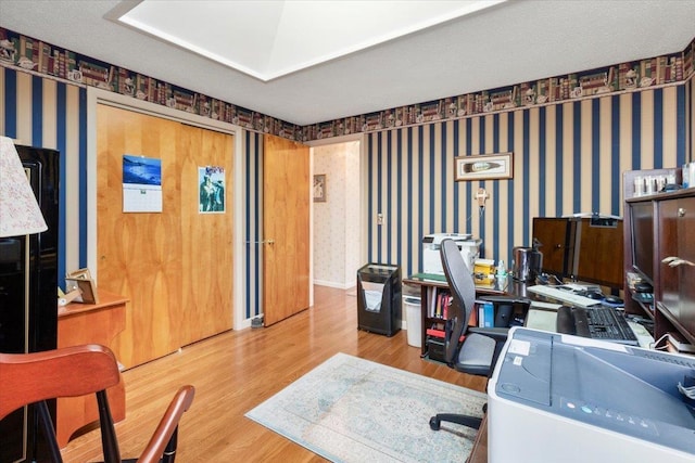 home office with wallpapered walls, baseboards, and wood finished floors